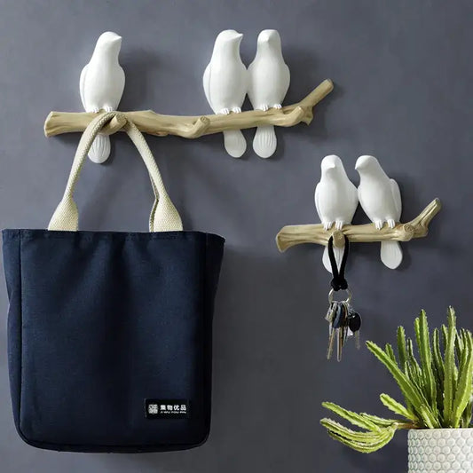 White decorbites bird resin hanger with white ceramic bird wall hooks mounted on a natural wood branch
