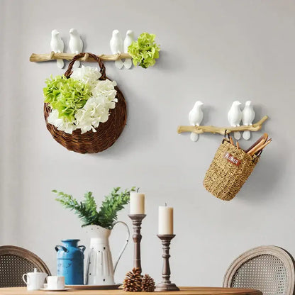 Woven brown basket hanging from a rustic wooden branch with white and green hydrangeas on decorbites bird resin hanger