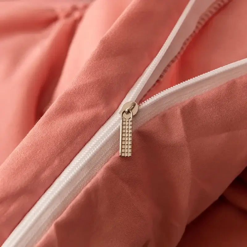 A delicate gold-toned zipper pull on a white diamond pinch pleated peach duvet cover set for bedroom bedding