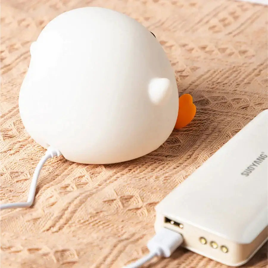 White duck silicone night light with orange beak and touch sensor timer plugged into a white power bank decorbites duck silicone