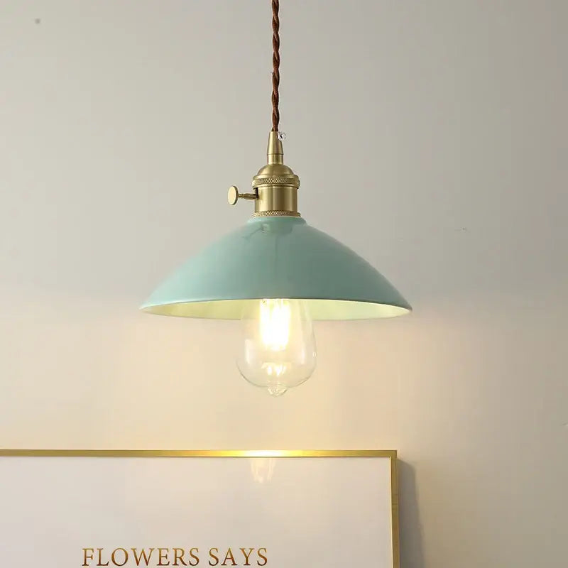 A mint green metal pendant light with brass fixture and twisted cord featuring decorbites ceramic knob switch