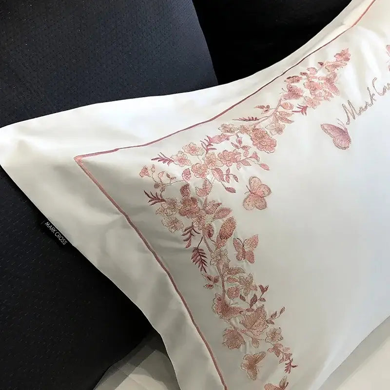 White satin pillowcase with pink floral and butterfly embroidery and red piping from egyptian cotton bedding sets