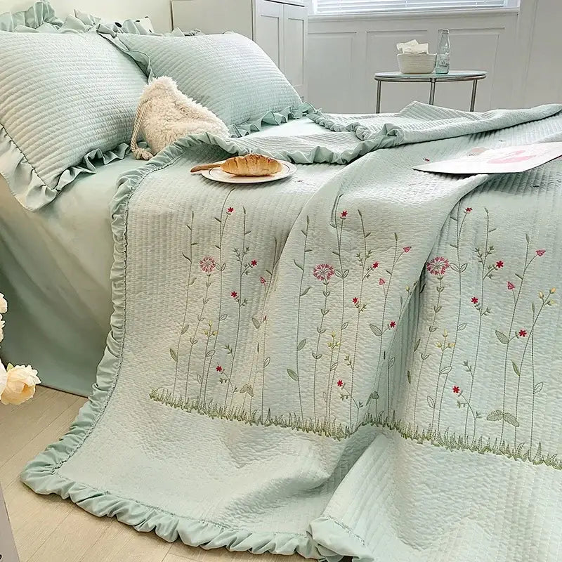 A soft mint green quilt set with fresh flower embroidered pink and green floral design and ruffled cotton bedding edge
