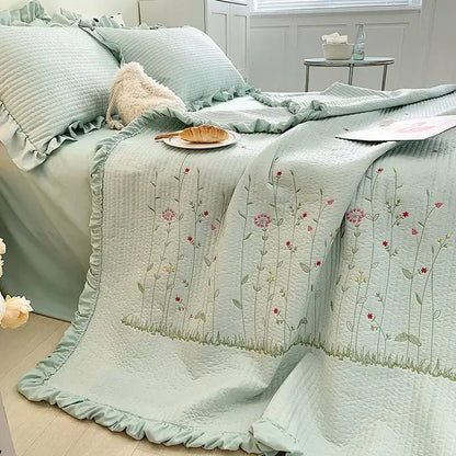 A soft mint green quilt set with fresh flower embroidered pink and green floral design and ruffled cotton bedding edge