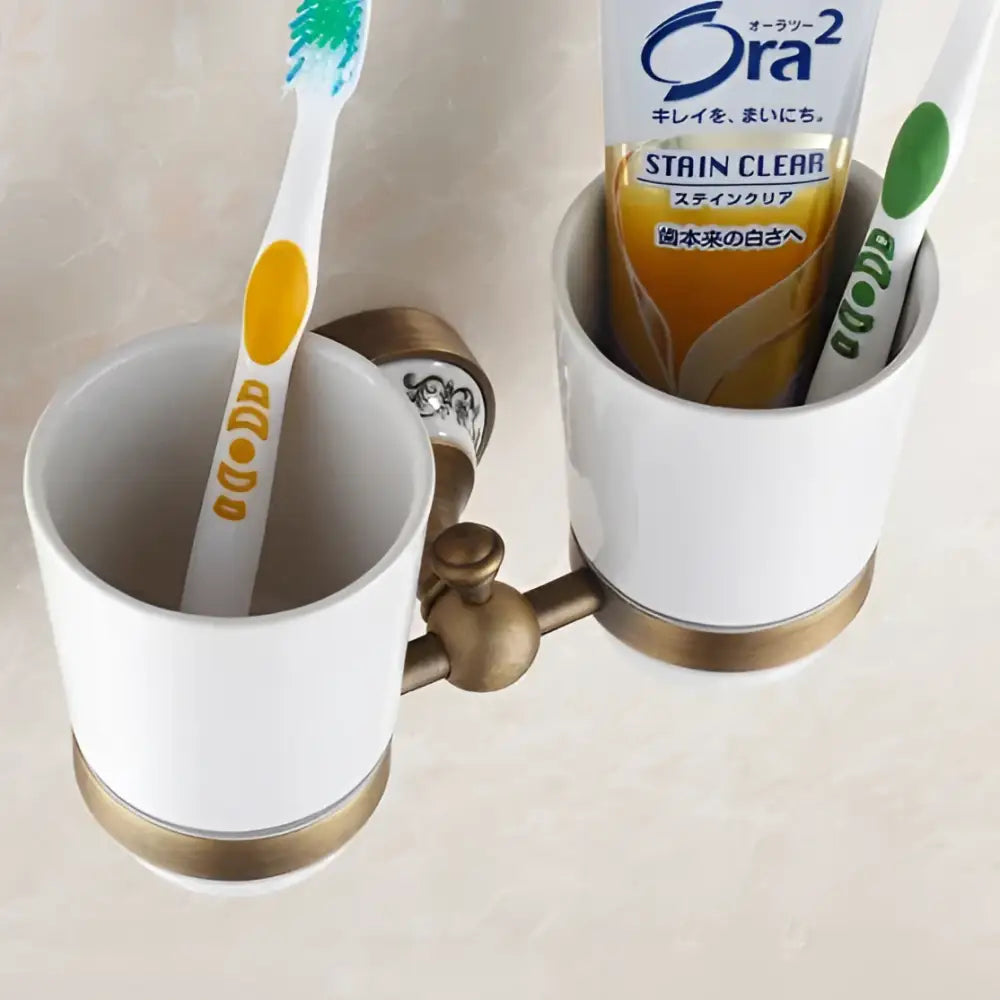 White ceramic toothbrush holder with gold-toned brass accents and curved handle for decorbites brass toothbrush accessory