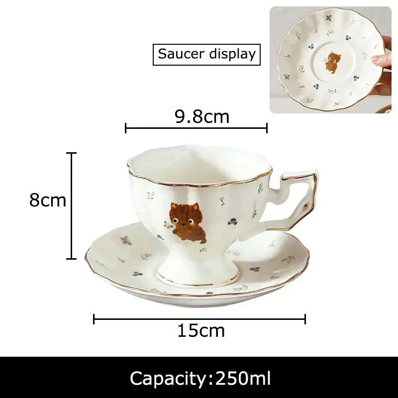 White ceramic mug and saucer with gold trim featuring a brown cartoon kitten pattern for dining room use
