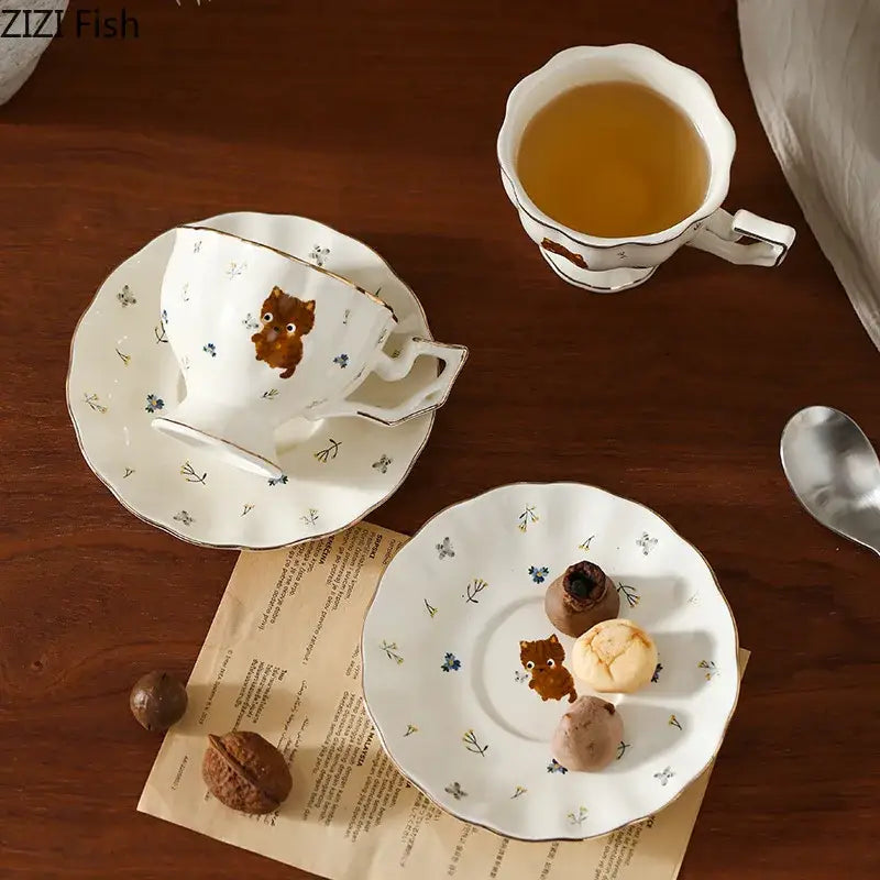 White ceramic teacup and saucer with gold trim featuring a brown cartoon kitten pattern for dining room use