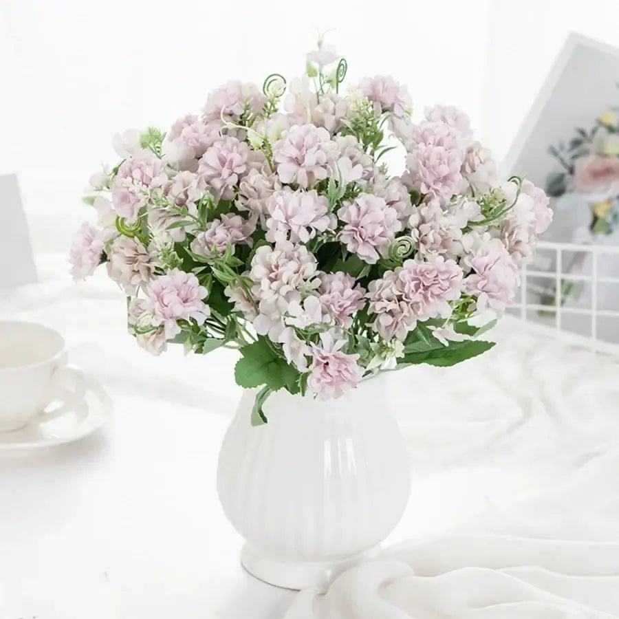 White hydrangea bouquet of light pink artificial flowers with green stems in a ribbed ceramic vase for living room decor