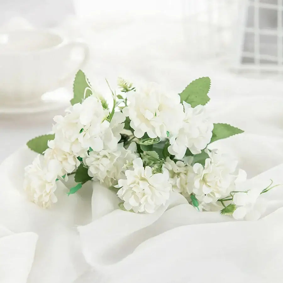 A delicate artificial white hydrangea bouquet with soft petals and green leaves in a ribbed glass vase for living room decorbites hydrangea bouquet