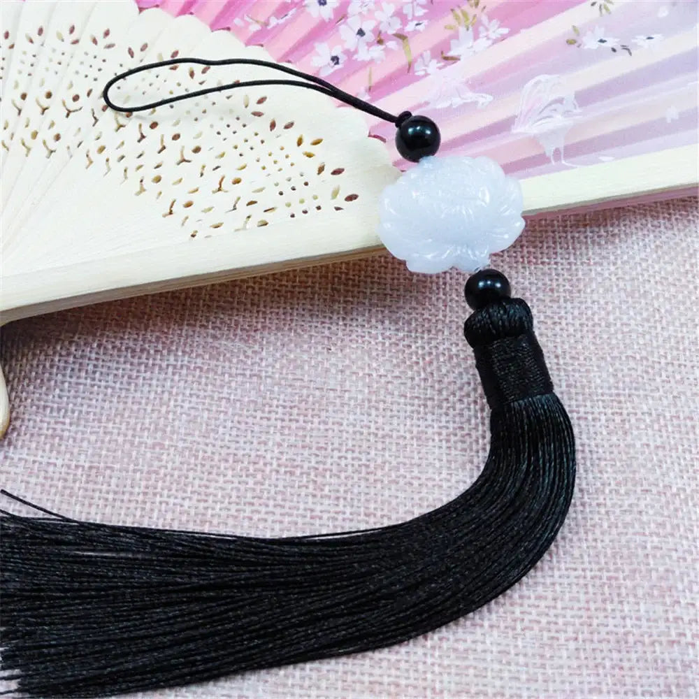 A delicate white jade lotus pendant with black beads and a long black tassel for living room decor