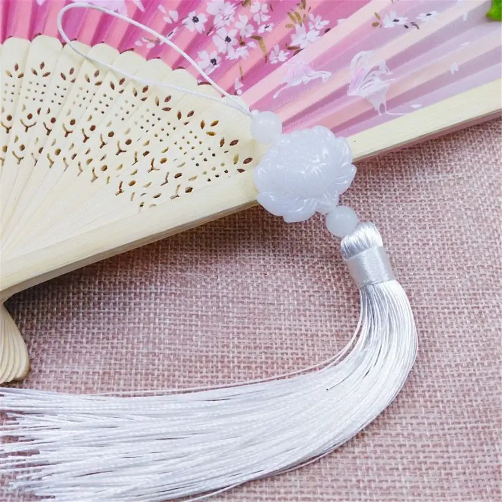 A delicate white jade lotus tassel decorative pendant with carved floral design and silver-threaded fringe for living room decor