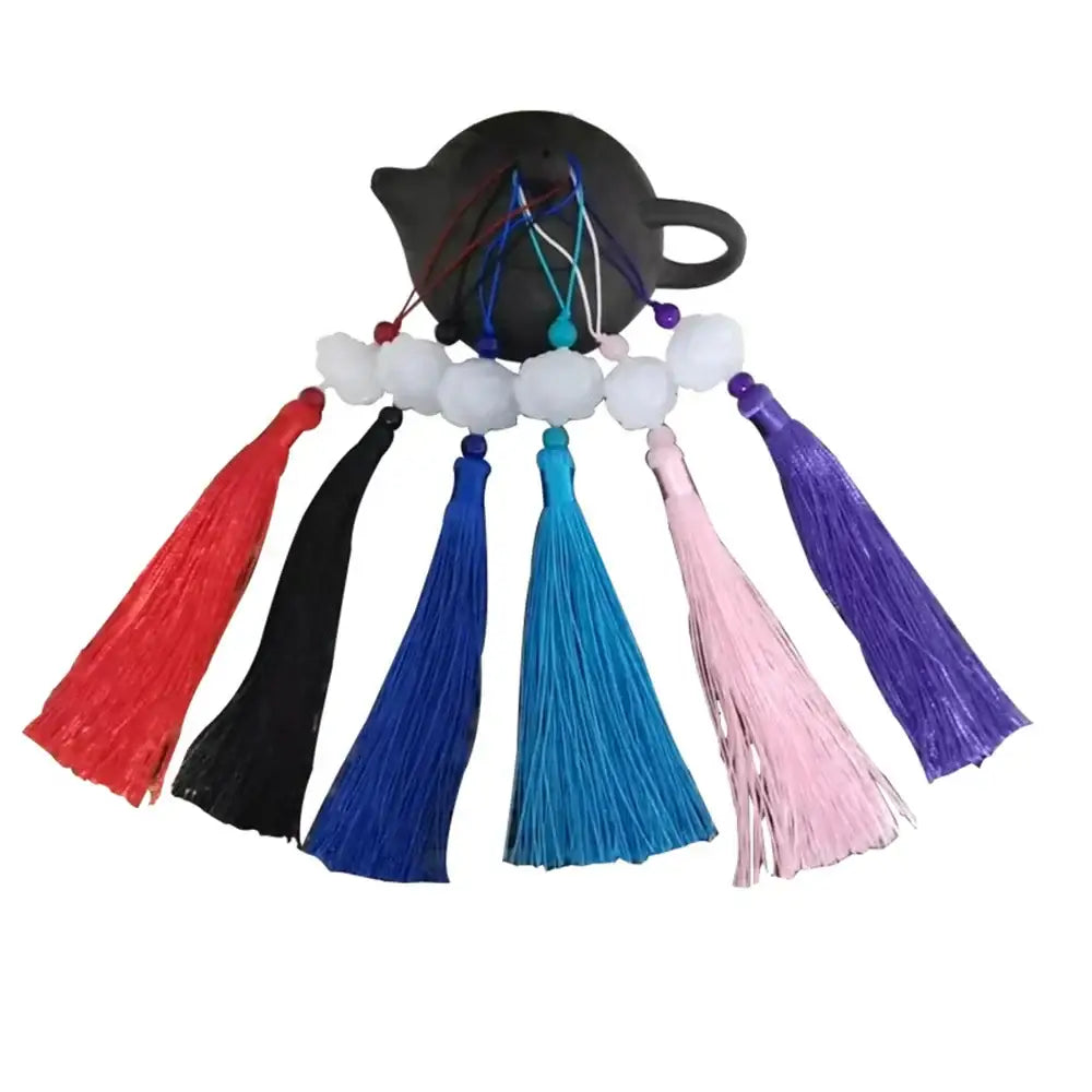 A set of colorful tassel decorative pendants with white jade lotus beads arranged around a dark ceramic teapot