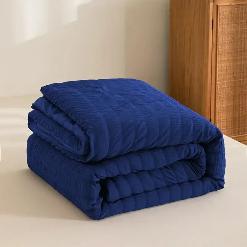A plush deep blue king size seersucker quilt with textured ribbed surface for all season comfort and decorbites style