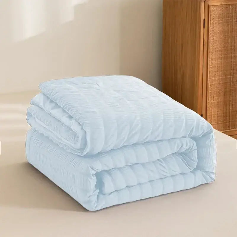 A soft light blue decorbites king size seersucker quilt with subtle ribbed texture and neatly folded edges