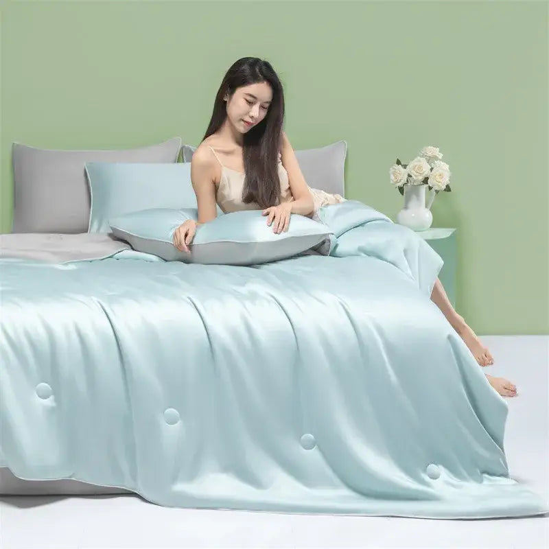 A soft light blue satin decorbites cool feel summer quilt with subtle button detailing for a cool feel summer bedroom