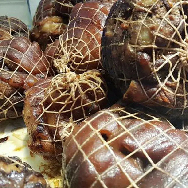 Crisp golden-brown braised pork trotters tied with natural twine in a white mesh bbq net bundle for roasting