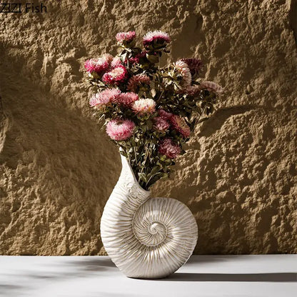 White nautilus conch ceramic vase from decorbites holding dried pink and purple flowers for bedroom and office decor