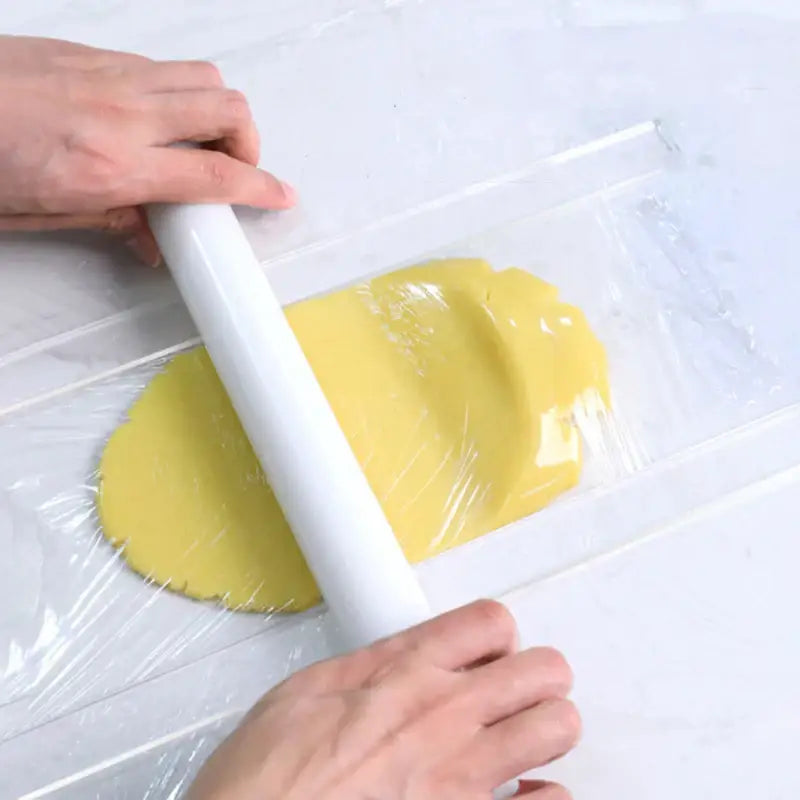 A white plastic biscuit cake rolling tool is used to flatten yellow dough with a cake rolling tool ruler decorbites biscuit cake