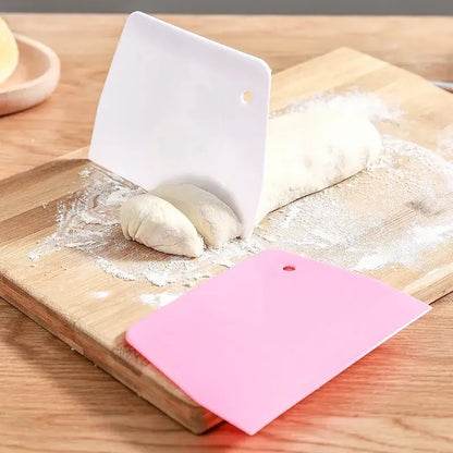 White and pink silicone cake cutter spatula set on wooden board for dough cream cake cutting and baking tasks