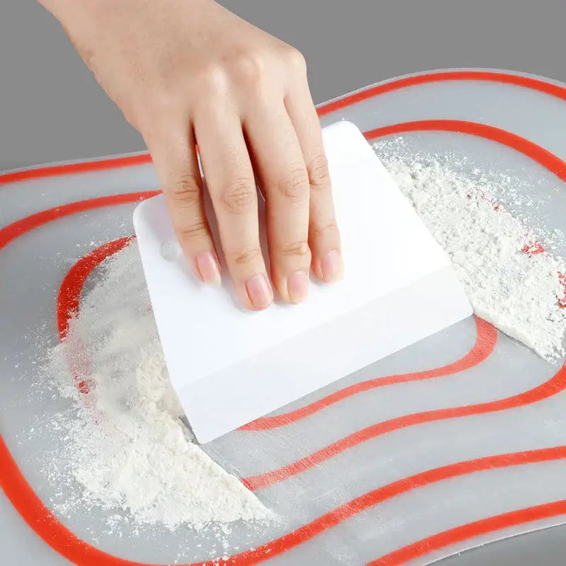 White plastic dough cream cake cutter spatula made of silicone used for scraping flour from baking surface