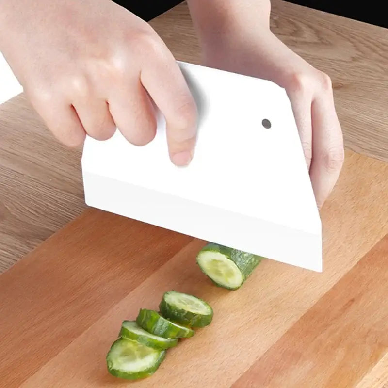 White plastic cream cake cutter spatula with small black dot slicing cucumbers for dough cream cake preparation