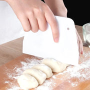 White plastic dough cream cake cutter spatula with rounded handle and small hole for kitchen baking use