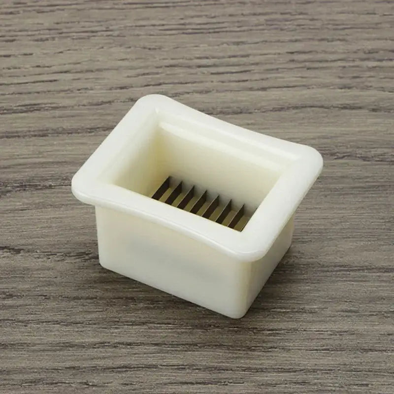 White plastic green bean slicer with rectangular shape and multiple thin metal blades for vegetable shredding
