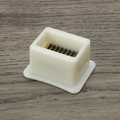White plastic green bean slicer with square base and internal metal blades for efficient vegetable shredding