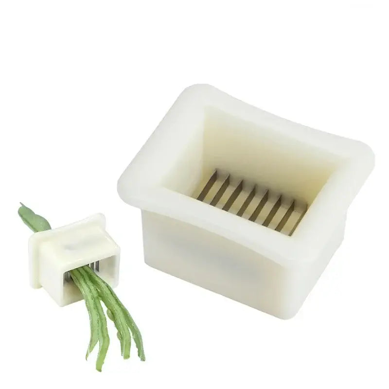 White plastic green bean slicer with metal blades cutting fresh green beans for efficient kitchen shredding