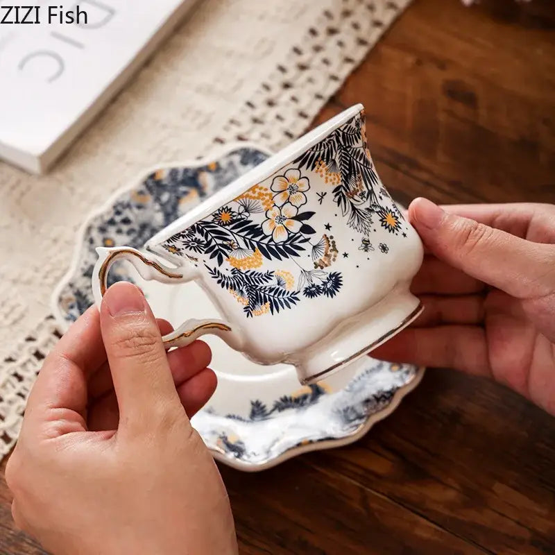 White porcelain classic teacup with gold-trimmed handle and rim featuring an intricate black and yellow floral pattern