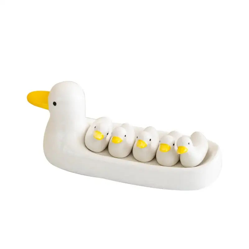 White porcelain duck chopstick holder tray featuring a ceramic dish with five smaller white ducks with yellow beaks nestled inside