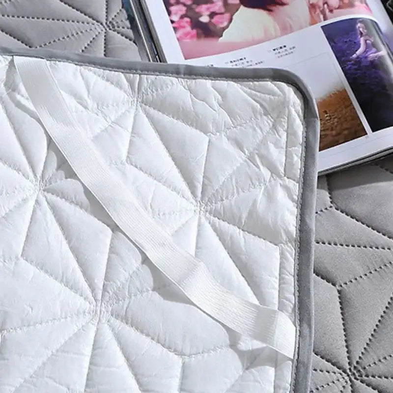 White quilted star pattern bed protector pad with gray border and elastic strap for secure fit on bed protector