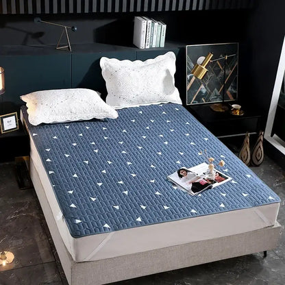 Blue quilted bed protector pad with white triangular patterns designed as a waterproof bedroom protector pad