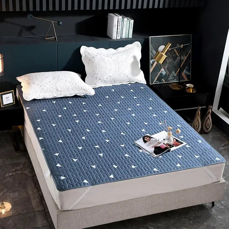 Blue quilted bed protector pad with white triangular patterns designed as a waterproof bedroom protector pad