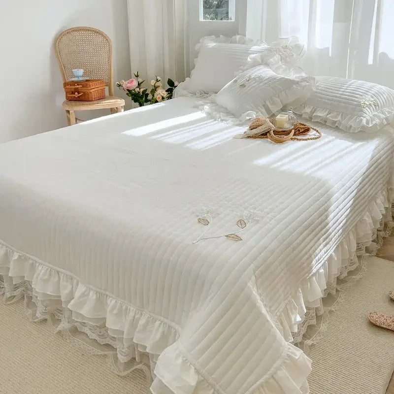 White quilted bedspread coverlet with delicate ruffled edges and embroidered leaf lace for bedroom use