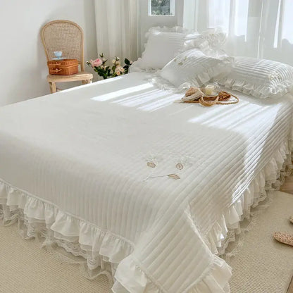 White quilted bedspread coverlet with delicate ruffled edges and embroidered leaf lace for bedroom use