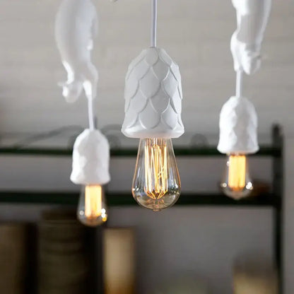 White ceramic pinecone-shaped pendant light with visible edison bulb serving as a bedroom decorative focal point