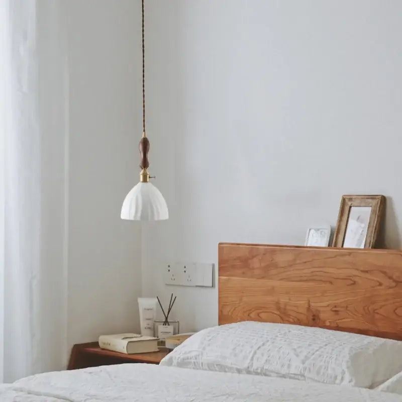 White textured glass ceramic led pendant light with brass fixture and dark brown cord decorbites ceramic led hanging above bed