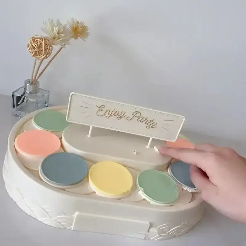 White two tiered rotating dessert table with pastel circular makeup palettes and enjoy party sign for dining room use