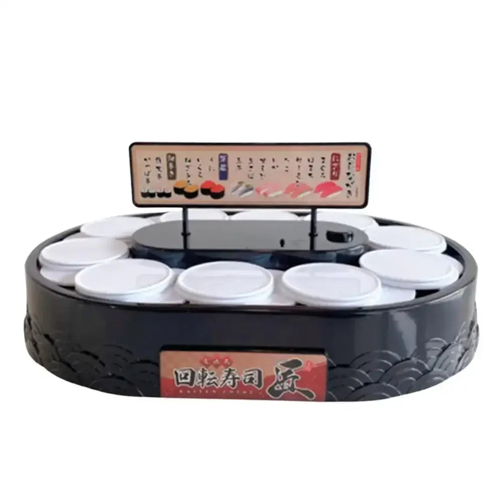 Black circular sushi machine with white lids on a two tiered rotating dessert table with menu sign above