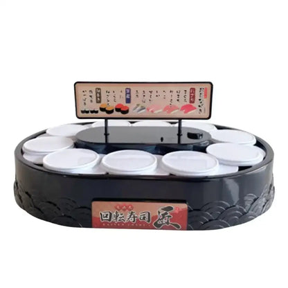 Black circular sushi machine with white lids on a two tiered rotating dessert table with menu sign above