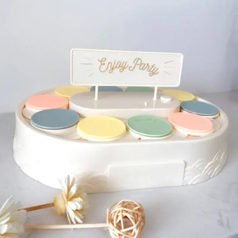 Pastel-colored circular compartment organizer with enjoy party sign on top for white two tiered rotating dessert table sushi machine