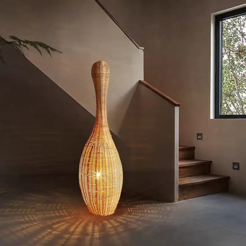 A warm light bamboo floor lamp with a dark brown woven rattan base and slender neck for living room decorbites decor