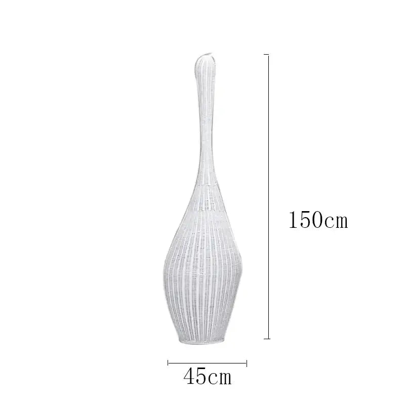 A tall slender white woven vase with a flared top complementing decorbites bamboo floor lamp for warm living room light