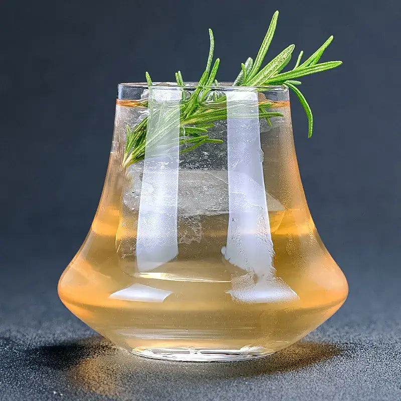 Wind edge crystal whiskey glass tumbler filled with amber cocktail and garnished with fresh rosemary sprig decorbites crystal whiskey