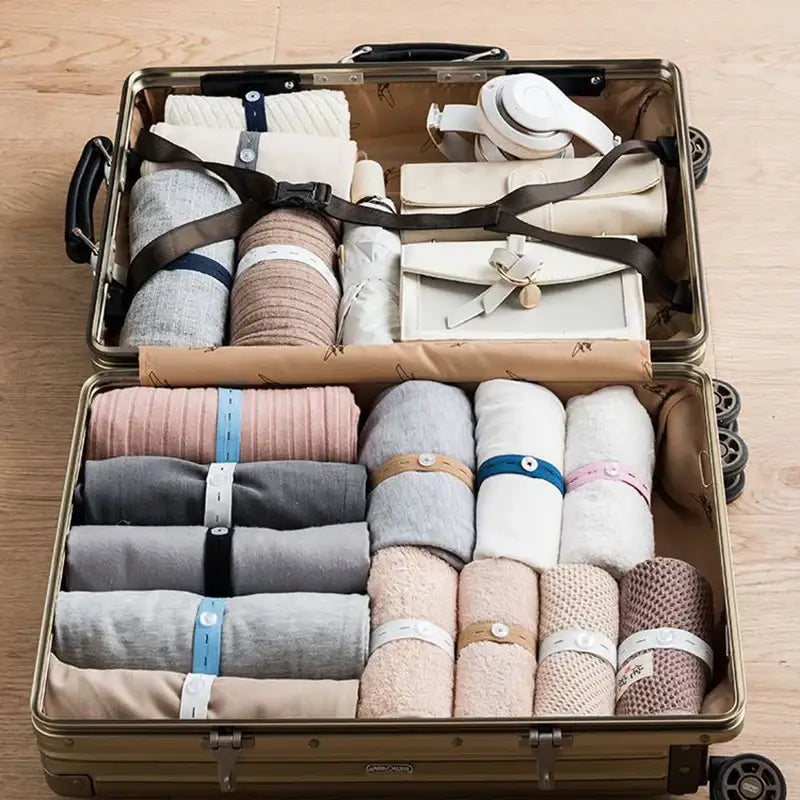 Gold-colored hard-shell suitcase with black handles packed with colorful wooden button elastic band clothes folding storage bags