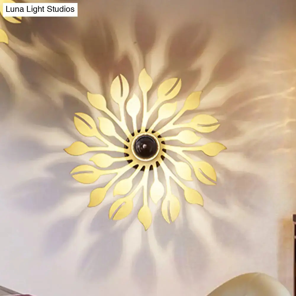 Gold-toned leaf-shaped wooden floral wall lamp with central black element for orange and yellow bedroom lighting