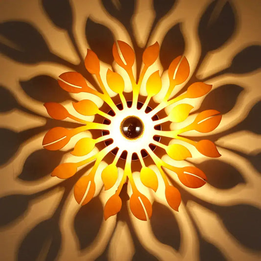 A warm glowing wooden floral sunburst wall lamp with orange and yellow leaf-shaped panels for bedroom lighting