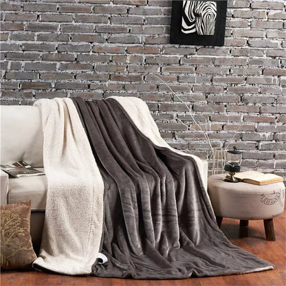 A plush two toned wool throw blanket with soft gray exterior and creamy white interior draped over a sofa for warmth