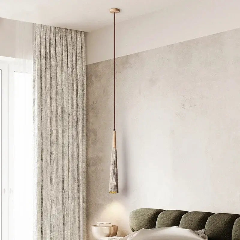 Woven beige pendant light with wood accents featuring a copper-toned rod and gray tassel decorbites designer pendant light